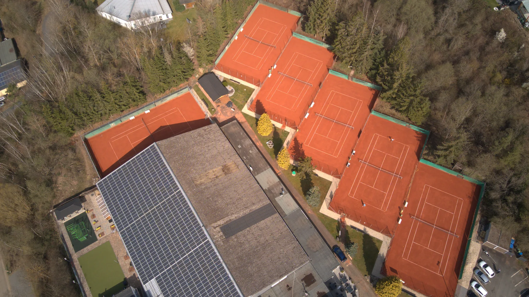 Blick von oben auf die gestaffelten Sandplätze und das Clubhaus des TC Grün-Weiß Elz.